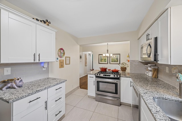 179 County Road F W, Shoreview, MN 55126 - kitchen featuring stainless steel appliances, tasteful backsplash, a chandelier, white cabinets, and light tile patterned floors