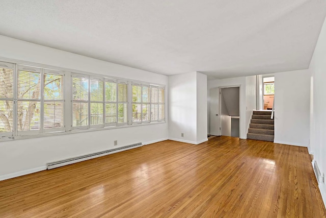 3671 Robinwood Ter, Minnetonka, MN 55305 - unfurnished living room featuring baseboard heating, stairs, light wood-type flooring, and baseboards