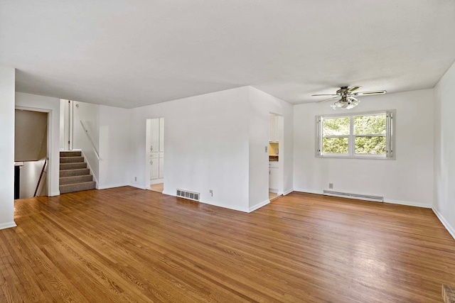 3671 Robinwood Ter, Minnetonka, MN 55305 - unfurnished living room with baseboard heating, wood finished floors, stairway, ceiling fan, and baseboards