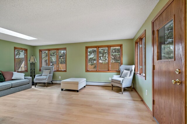 3004 36th Ave NE, Saint Anthony, MN 55418 - living room with plenty of natural light, a textured ceiling, light wood finished floors, a skylight, and a baseboard radiator