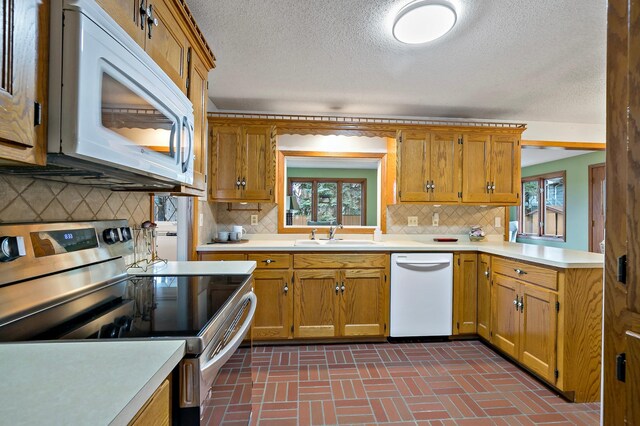 3004 36th Ave NE, Saint Anthony, MN 55418 - kitchen featuring white appliances, light countertops, a sink, a textured ceiling, and brick patterned floors