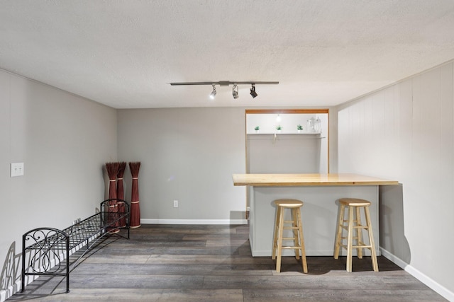 9320 Revere Ln N, Maple Grove, MN 55369 - kitchen with dark wood-style flooring, a textured ceiling, a breakfast bar, rail lighting, and wooden counters