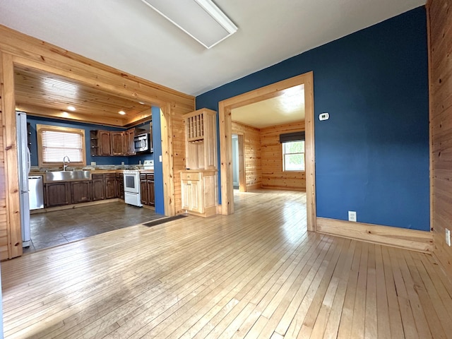 638 James St, Ely, MN 55731 - kitchen with appliances with stainless steel finishes, a sink, wooden walls, dark wood-style floors, and light countertops