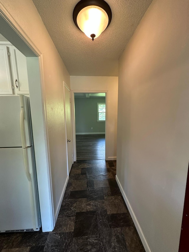 332 Pleasant Ave, Ellsworth, WI 54011 - hall featuring a textured ceiling, baseboards, and dark stone finish flooring