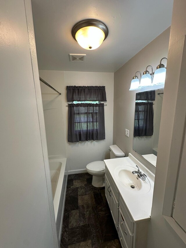 332 Pleasant Ave, Ellsworth, WI 54011 - bathroom with vanity, stone finish floors, toilet, and shower / washtub combination