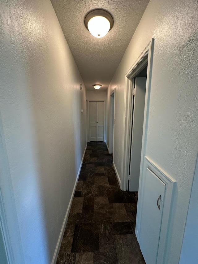 332 Pleasant Ave, Ellsworth, WI 54011 - hall featuring a textured ceiling, stone finish floors, and baseboards