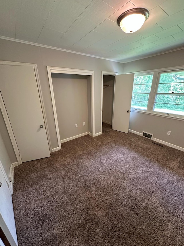332 Pleasant Ave, Ellsworth, WI 54011 - unfurnished bedroom featuring dark colored carpet, crown molding, multiple closets, and baseboards