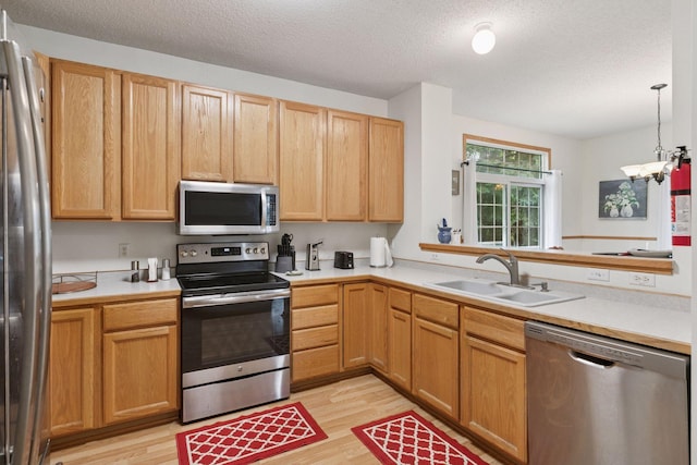 9026 Merrimac Ln N, Maple Grove, MN 55311 - kitchen featuring appliances with stainless steel finishes, a sink, light wood-style flooring, a textured ceiling, and light countertops