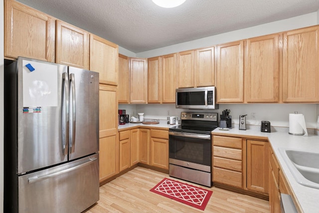 9026 Merrimac Ln N, Maple Grove, MN 55311 - kitchen featuring stainless steel appliances, light brown cabinetry, light wood-style flooring, and a textured ceiling