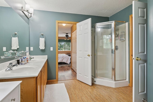 9026 Merrimac Ln N, Maple Grove, MN 55311 - ensuite bathroom with double vanity, a stall shower, a ceiling fan, a textured ceiling, and wood finished floors
