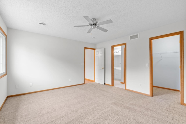 5423 Elm Grove Ave, New Hope, MN 55428 - unfurnished bedroom featuring a walk in closet, light colored carpet, a textured ceiling, connected bathroom, and a closet