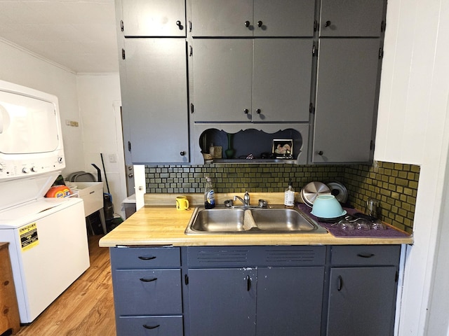 702 Junius Ave, Fergus Falls, MN 56537 - kitchen featuring a sink, estacked washer and dryer, light wood finished floors, decorative backsplash, and light countertops
