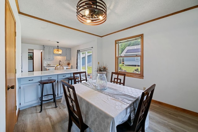 6567 Shore Trl N, Forest Lake, MN 55025 - dining area featuring wood finished floors, a chandelier, crown molding, and a textured ceiling