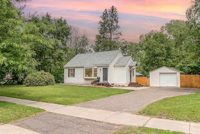 2211 108th Ave NW, Coon Rapids, MN 55433 - view of front facade featuring an outbuilding, asphalt driveway, a detached garage, a shingled roof, and view of scattered trees