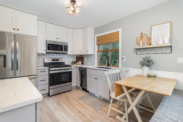 2211 108th Ave NW, Coon Rapids, MN 55433 - kitchen featuring stainless steel appliances, a sink, tasteful backsplash, light stone counters, and light wood-style floors