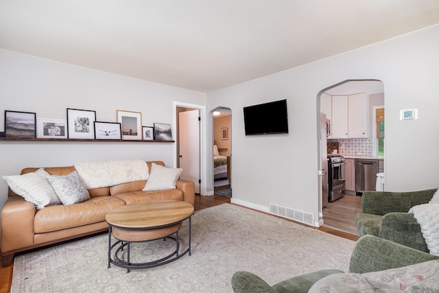 2211 108th Ave NW, Coon Rapids, MN 55433 - living room featuring arched walkways, light wood finished floors, and baseboards