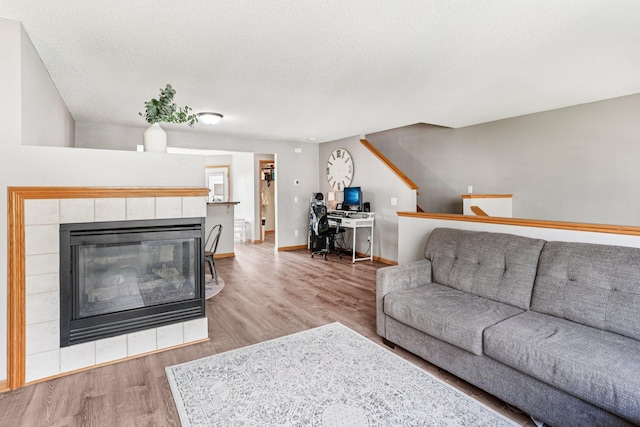 15040 Farnham Ave N, Hugo, MN 55038 - living area with wood finished floors, a tiled fireplace, and a textured ceiling