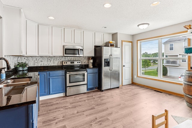 15040 Farnham Ave N, Hugo, MN 55038 - kitchen featuring appliances with stainless steel finishes, blue cabinetry, dark countertops, a textured ceiling, and backsplash