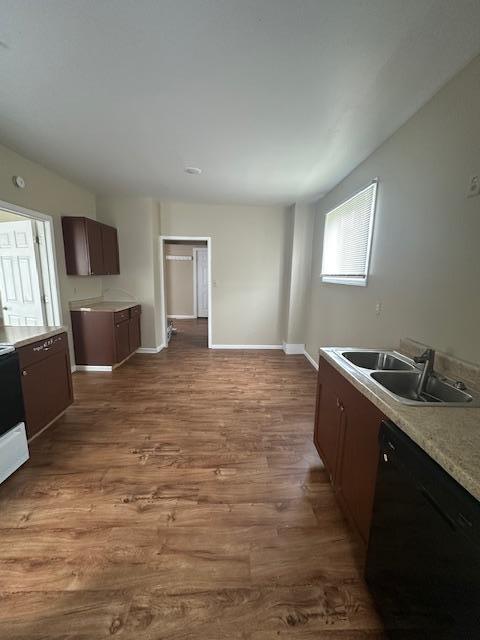 2014 Oakland Ave, Austin, MN 55912 - kitchen featuring dishwasher, light countertops, dark wood-style flooring, a sink, and baseboards