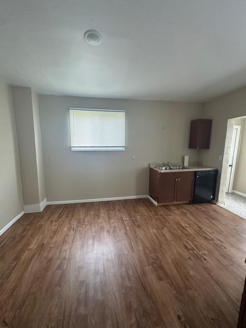 2014 Oakland Ave, Austin, MN 55912 - unfurnished living room featuring dark wood-style flooring, a sink, and baseboards