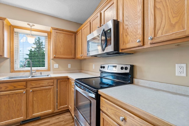 3168 Molina St, Shakopee, MN 55379 - kitchen with stainless steel appliances, light countertops, pendant lighting, light wood-type flooring, and a textured ceiling