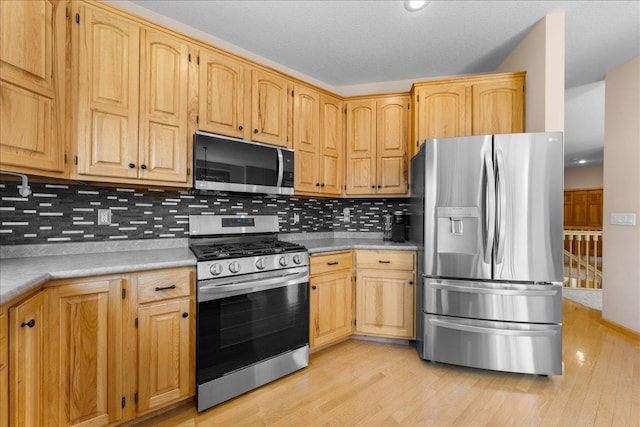 1195 64th St, Hudson, WI 54016 - kitchen featuring stainless steel appliances, decorative backsplash, light wood-type flooring, and light countertops