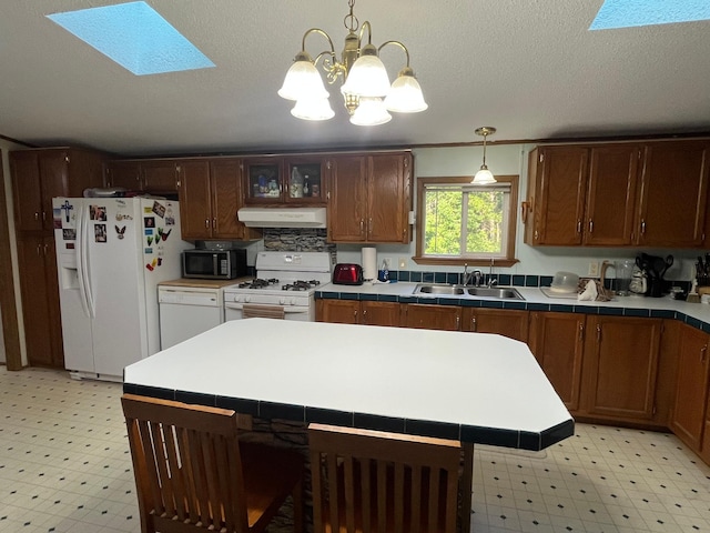 23324 State Highway 107, Grasston, MN 55030 - kitchen with white appliances, under cabinet range hood, light floors, and a skylight