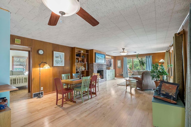 895 Front, Saint Paul, MN 55103 - dining area featuring ceiling fan, light wood-type flooring, wood walls, and a fireplace