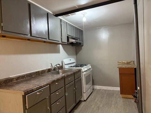 845 Sims Ave, Saint Paul, MN 55106 - kitchen with gas range gas stove, a sink, under cabinet range hood, light wood-type flooring, and dark countertops