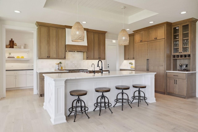 21281 Dorothy Way, Spring Lake Twp, MN 55372 - kitchen featuring brown cabinets, light wood-style flooring, recessed lighting, tasteful backsplash, and an island with sink