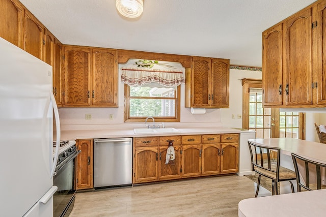 10275 Park Cir, Pine City, MN 55063 - kitchen with stainless steel dishwasher, freestanding refrigerator, gas range, brown cabinets, and a sink