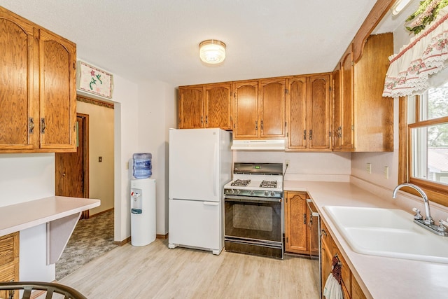 10275 Park Cir, Pine City, MN 55063 - kitchen featuring range with gas cooktop, freestanding refrigerator, a sink, under cabinet range hood, and brown cabinets