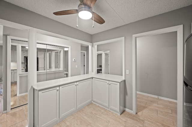 2455 Londin Ln E Unit 216, Maplewood, MN 55119 - kitchen featuring ceiling fan, light countertops, white cabinetry, a textured ceiling, and freestanding refrigerator
