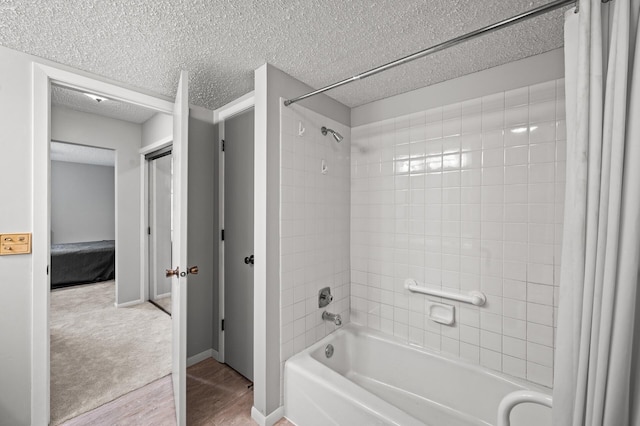 2455 Londin Ln E Unit 216, Maplewood, MN 55119 - bathroom featuring shower / bathtub combination with curtain, a textured ceiling, and wood finished floors