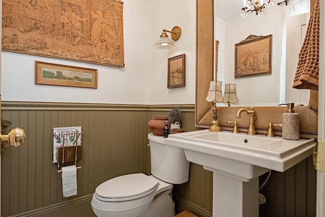 72 Mill St, Winona, MN 55987 - half bathroom featuring toilet, wainscoting, and a chandelier