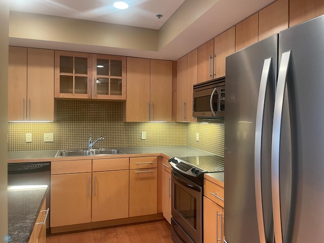 319 Broadway N Unit 207, Fargo, ND 58102 - kitchen with stainless steel appliances, a sink, decorative backsplash, light wood-type flooring, and glass insert cabinets