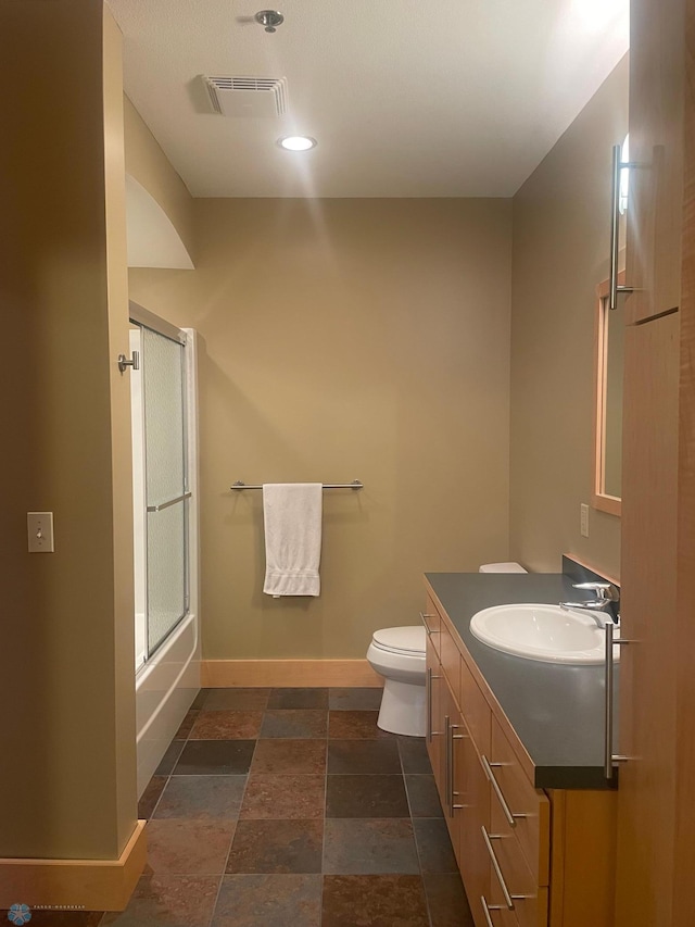 319 Broadway N Unit 207, Fargo, ND 58102 - bathroom with baseboards, toilet, vanity, stone finish flooring, and enclosed tub / shower combo