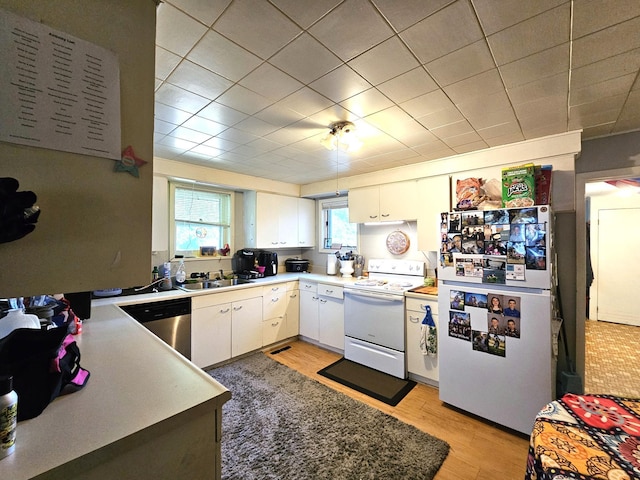 214 Vasa Ave, Fergus Falls, MN 56537 - kitchen with white appliances, white cabinets, light wood-style flooring, light countertops, and a sink