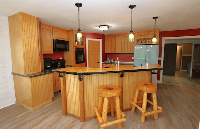 39192 460th Ave, Perham, MN 56573 - kitchen with black appliances, light wood-style flooring, a kitchen island with sink, and a breakfast bar area