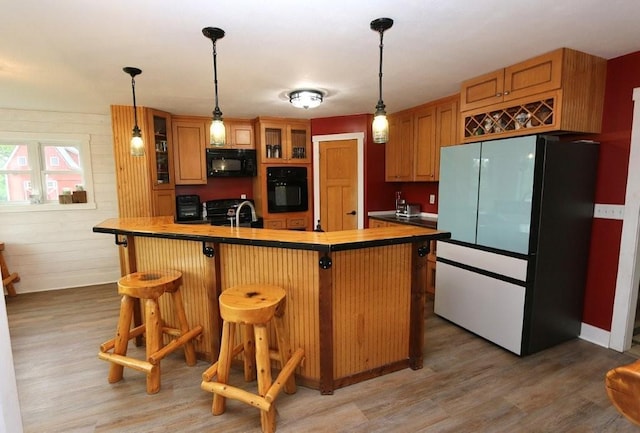 39192 460th Ave, Perham, MN 56573 - kitchen with black appliances, light wood-type flooring, glass insert cabinets, a breakfast bar area, and pendant lighting