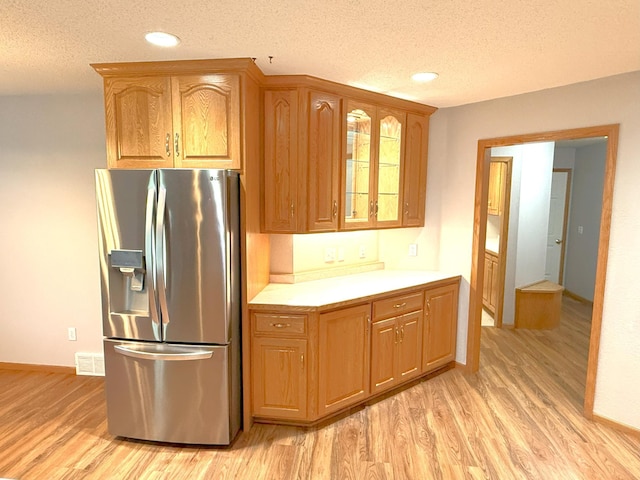 1423 Fairview Ln, Little Falls, MN 56345 - kitchen with stainless steel fridge with ice dispenser, light wood-style flooring, a textured ceiling, light countertops, and glass insert cabinets