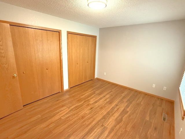 1423 Fairview Ln, Little Falls, MN 56345 - unfurnished bedroom featuring two closets, wood finished floors, and a textured ceiling