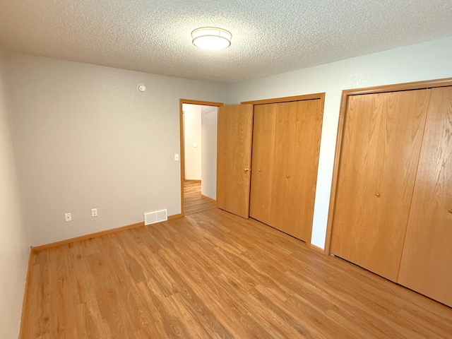 1423 Fairview Ln, Little Falls, MN 56345 - unfurnished bedroom with light wood-style floors, two closets, and a textured ceiling