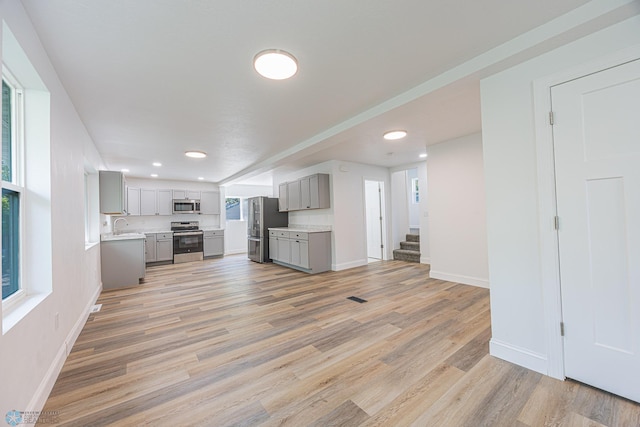 1814 5th St N, Fargo, ND 58102 - unfurnished living room featuring a sink, baseboards, recessed lighting, stairs, and light wood finished floors