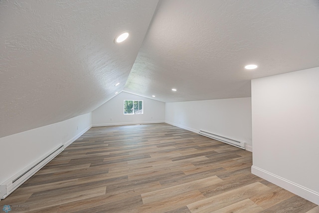 1814 5th St N, Fargo, ND 58102 - additional living space with a baseboard heating unit, a textured ceiling, baseboards, vaulted ceiling, and wood finished floors