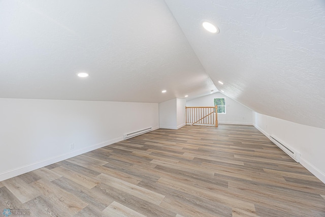 1814 5th St N, Fargo, ND 58102 - additional living space with a baseboard heating unit, vaulted ceiling, baseboards, light wood-style flooring, and a textured ceiling