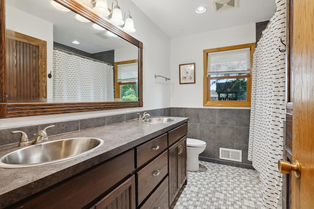 1412 10th Ave W, Shakopee, MN 55379 - bathroom with tile walls, toilet, double vanity, a wainscoted wall, and curtained shower