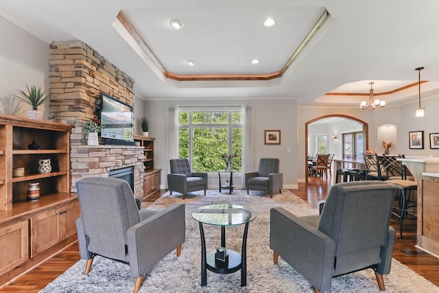 13478 Clearwater Cir, Rogers, MN 55374 - living area with a raised ceiling, crown molding, arched walkways, a fireplace, and wood finished floors