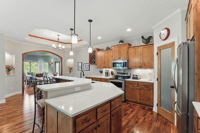 13478 Clearwater Cir, Rogers, MN 55374 - kitchen with appliances with stainless steel finishes, arched walkways, a kitchen island with sink, dark wood-style floors, and brown cabinets