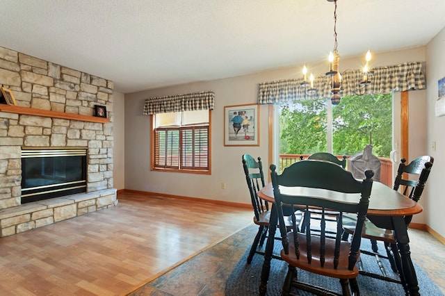 1580 9th Street Cir SE, Forest Lake, MN 55025 - dining area featuring a chandelier, baseboards, wood finished floors, a stone fireplace, and a textured ceiling